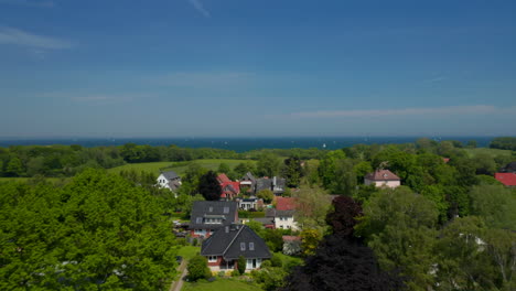 Aerial-view-flying-above-residential-suburbs-area-in-Brodten,-Germany,-drone-rises-up-reveal-amazing-Baltic-sea-landscape,-sunny-day